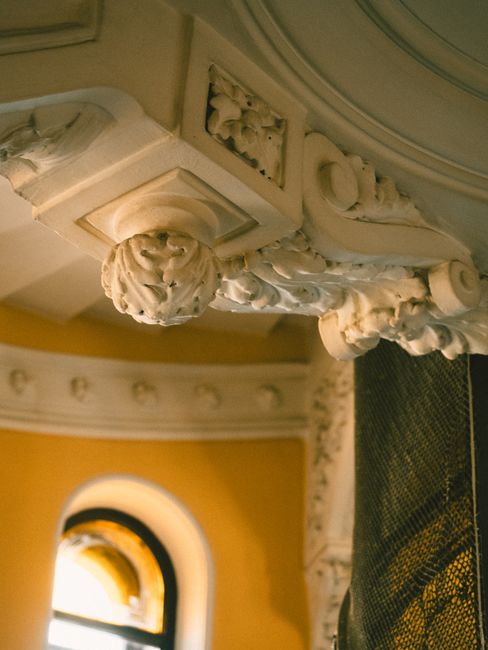 Detail of an ornate ceiling with intricate designs in warm lighting indoors.
