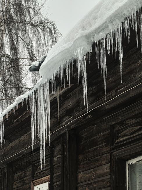 Captivating icicles hanging from a rustic snowy roof, showcasing winter's chill and beauty.