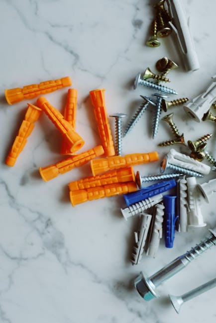 Bunch of various multicolored plastic dowels and metal screws arranged on white marble table in modern workshop